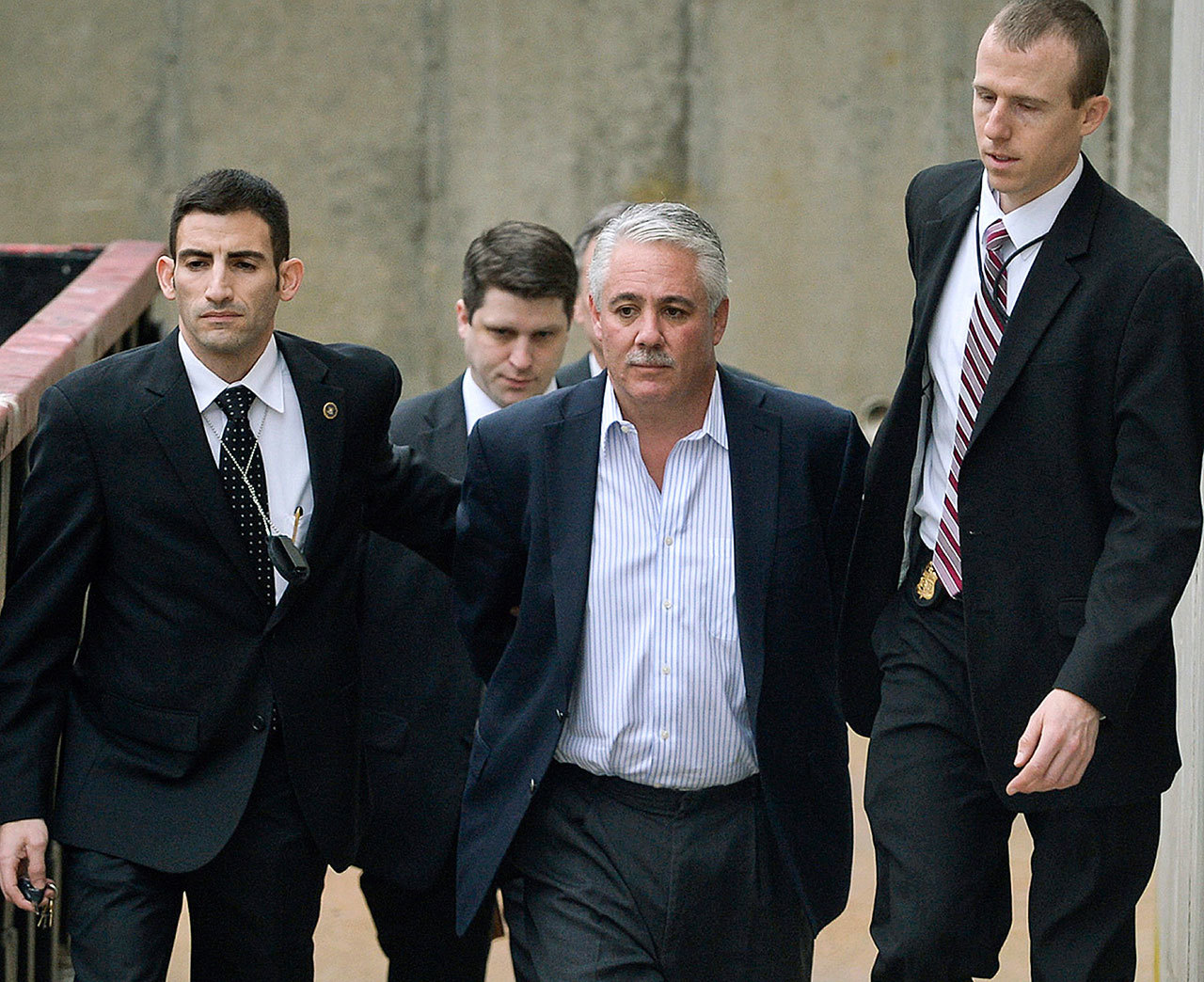 In this Dec. 9, 2015, photo, former Suffolk County Police Chief James Burke is escorted to a vehicle by FBI personnel outside an FBI office in Melville, New York. (Steve Pfost/Newsday via AP, File)