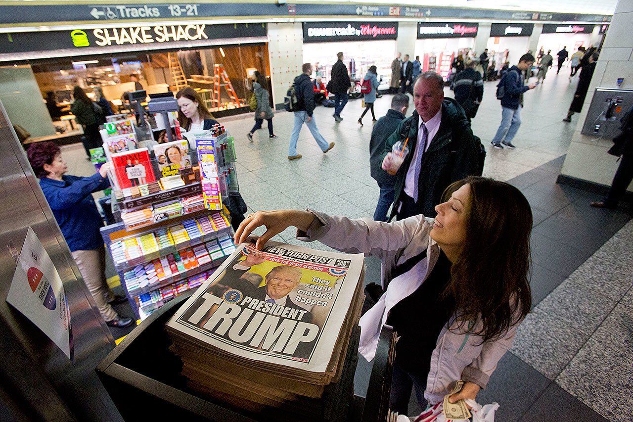 A woman reaches for a New York Post newspaper featuring president-elect Donald Trump’s victory Wednesday in New York. (AP Photo/Mark Lennihan)