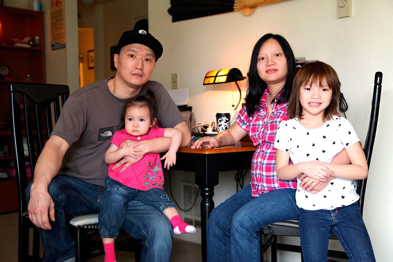 In this March 19, 2015, photo, Korean adoptee Adam Crapser, left, poses with daughters, Christal, 1, Christina, 5, and his wife, Anh Nguyen, in the family’s living room in Vancouver, Washington. (AP Photo/Gosia Wozniacka, File)