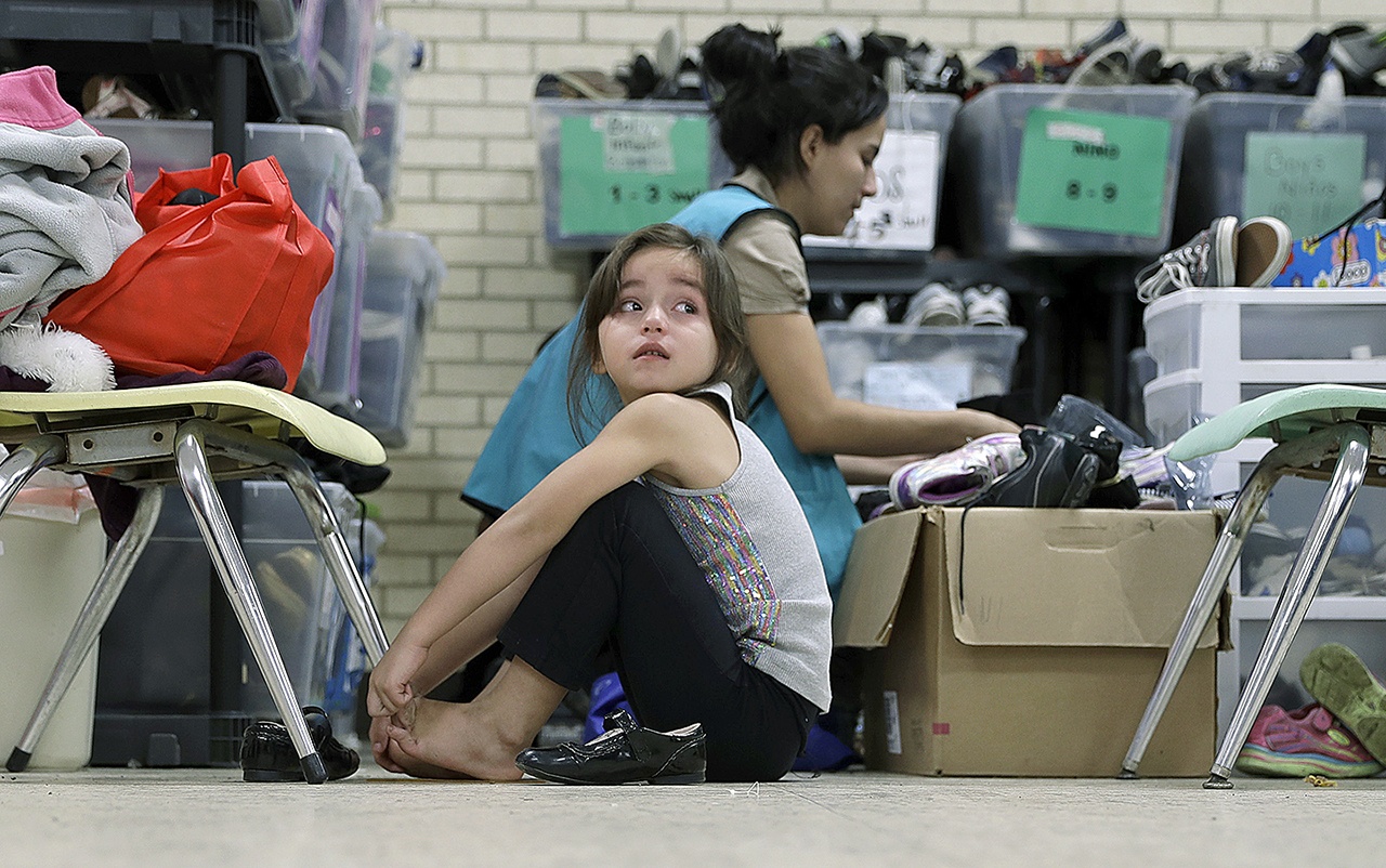 In this Nov. 13, photo, a young migrant girl from Central America, newly released after processing by the U.S. Customs and Border Patrol, is fitted shoes at the Sacred Heart Community Center in the Rio Grande Valley border city of McAllen, Texas. (AP Photo/Eric Gay)