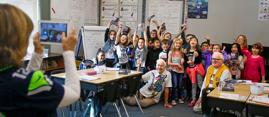 Kiwanis Club volunteers Jack Lapoint (center floor) and James Henry (right) pose with third-graders for teacher Christi Castro to photograph after giving the kids new dictionaries from the Kiwanis Club for the last time. (Dan Bates / The Herald)
