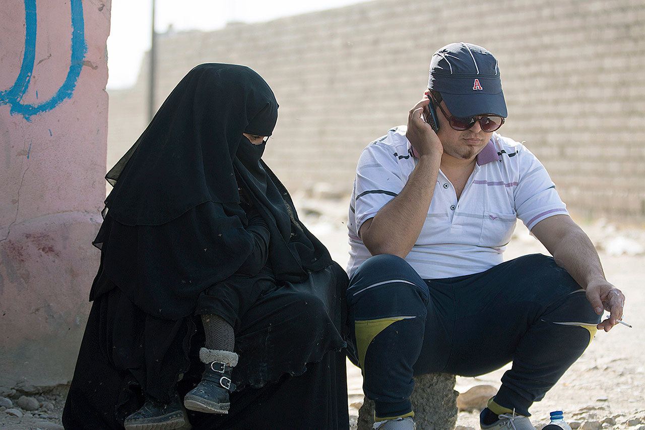 In this Sunday, Nov. 12, photo, a man who identified himself as Omar Danoun talks on the phone during an interview with The Associated press in Gogjali, Iraq. Danoun was taken into custody later in the interview by Iraqi soldiers who overheard and said he seemed to have a Syrian Accent, and who believed he was an Islamic Stage group member. (AP Photo/NishNalbandian)