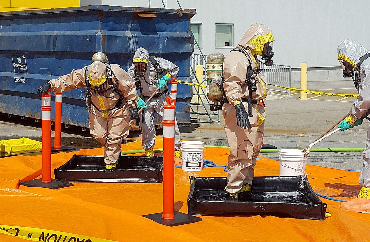 In this June 27, 2016, photo, members of the Royal Canadian Mounted Police go through a decontamination procedure in Vancouver after intercepting a package containing approximately 2.2 pounds of the powerful opioid carfentanil imported from China. (Royal Canadian Mounted Police via AP)
