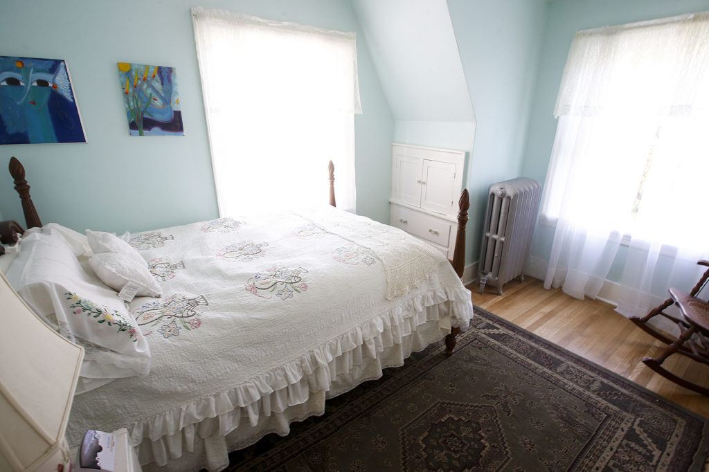 A renovated upstairs bedroom features light blue walls and white curtains for an airy feel. (Ian Terry / The Herald)
