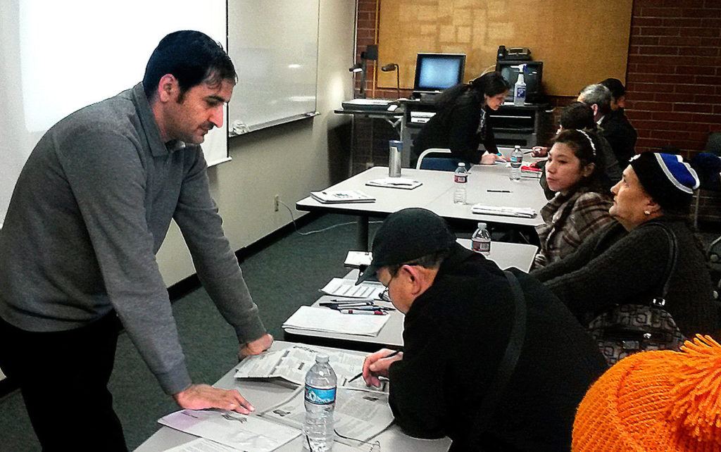 Kamal Acharya, who came from Bhutan and speaks Nepali, helps a voter understand the ballot. (Julie Muhlstein / The Herald)
