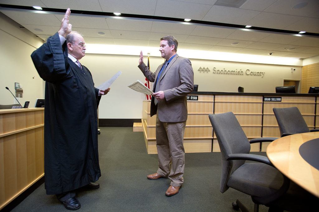Snohomish County Superior Court Judge Thomas Wynne administers the oath of office to new County Councilman Sam Low on Tuesday in Everett. (Andy Bronson / The Herald)
