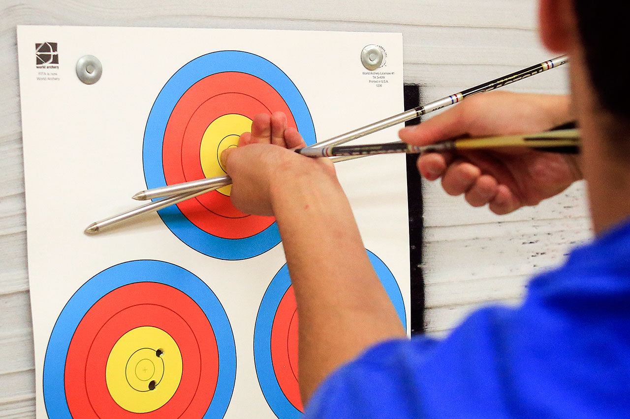 Mike Hooper extracts his arrows from a target at Nock Point Center in Mountlake Terrace on October 12, 2016. (Kevin Clark / The Herald)