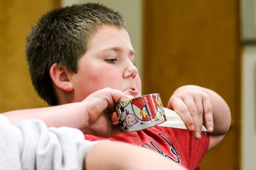 Austin Vangel, 12, unrolls another piece of duct tape for his wallet at Stanwood Library on Oct. 28. (Kevin Clark / The Herald)
