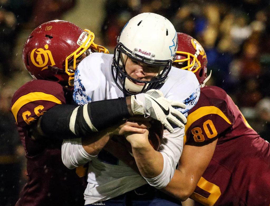 O’Dea’s Doug Russell (left) and Wayne Johnson converge to sack Meadowdale’s Drew Tingstad during a 3A state semifinal game Saturday at Pop Keeney Stadium in Bothell. O’Dea won 35-9. (Kevin Clark / The Herald)
