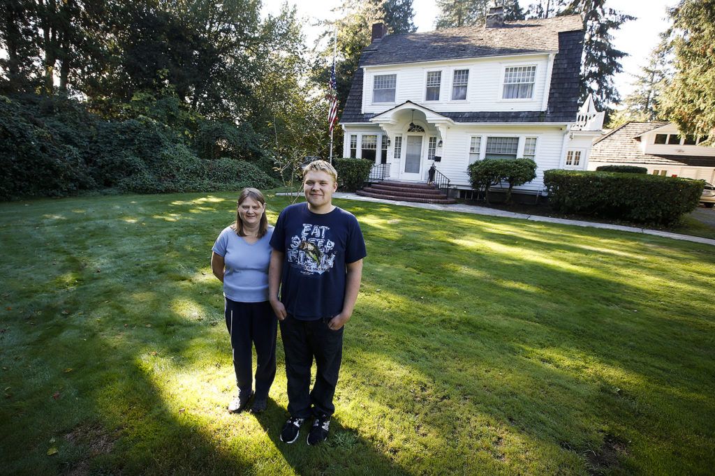 Jill Brumbaugh and her son, Joel Lidstrom, stand on the front lawn outside of their 4,000-square-foot renovated home in Monroe. (Ian Terry / The Herald)
