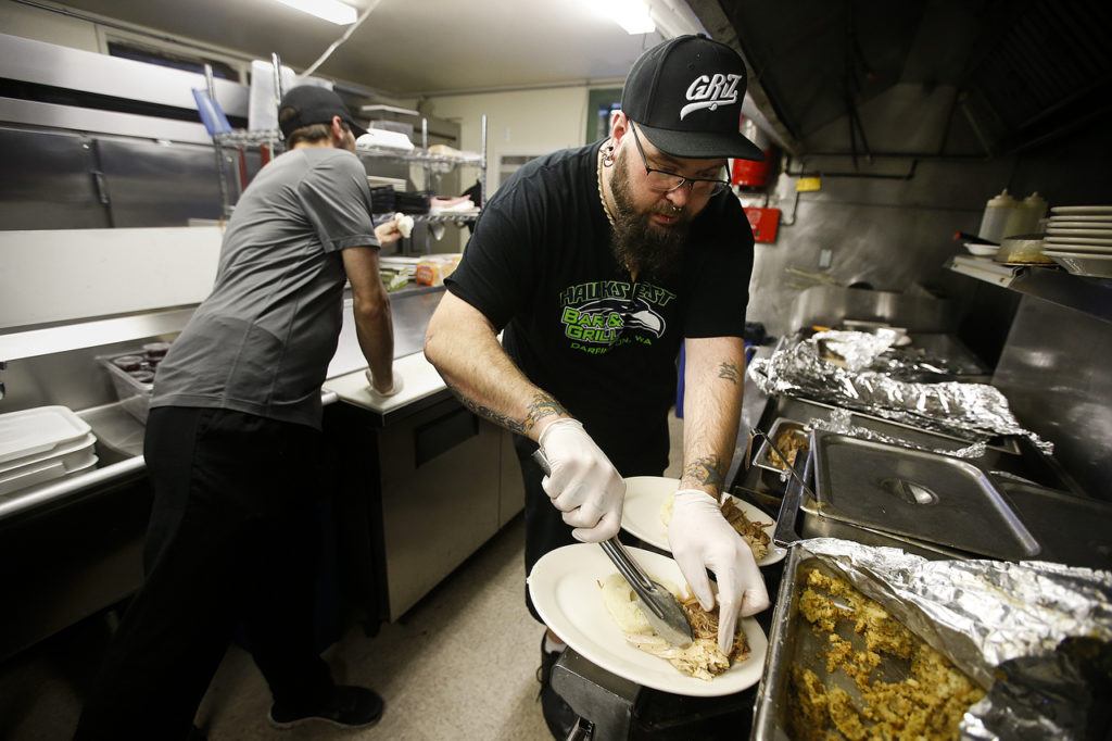 Randy Orsborn (right) dishes up a plate of smoked turkey at The Hawks Nest in Darrington on Thursday, Nov. 24. (Ian Terry / The Herald)
