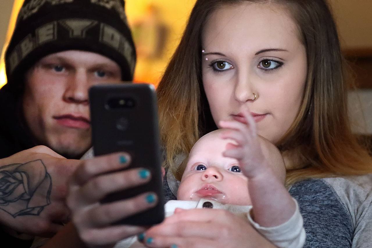 Jacob Varnes (left) looks over the shoulder of Jessiana King and his son Brayden Varner at her home in Granite Falls. (Kevin Clark / The Herald)