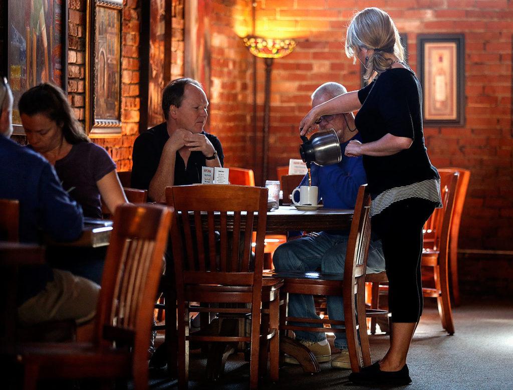 While late morning sun filters down through high windows, warming brick walls and playing on the slatted chairs, Vintage Cafe waitress, Jennifer Jarvis keeps the coffee flowing. Dan Bates / The Herald
