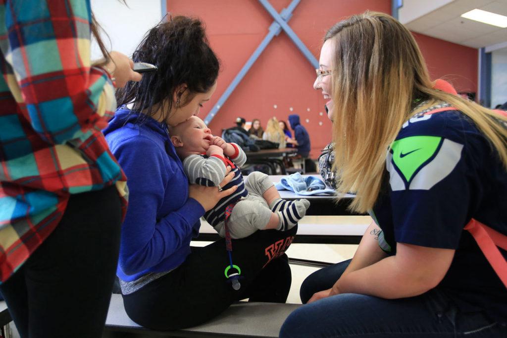 Chloe Ramirez holds Brayden Varnes with his mom, Jessiana King, looking on at Crossroads High School in Granite Falls. Crossroads offers childcare and King spends every lunch period with Brayden and friends. (Kevin Clark / The Herald)
