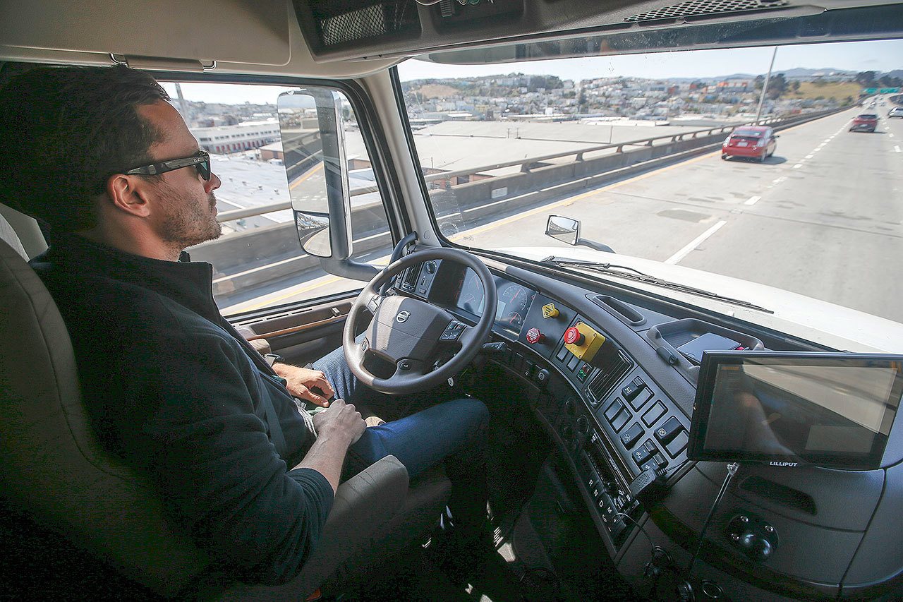 Matt Grigsby, senior program engineer at Otto, takes his hands off the steering wheel of a self-driving, big-rig truck during a demonstration on the highway, in San Francisco in August. (AP Photo / Tony Avelar)