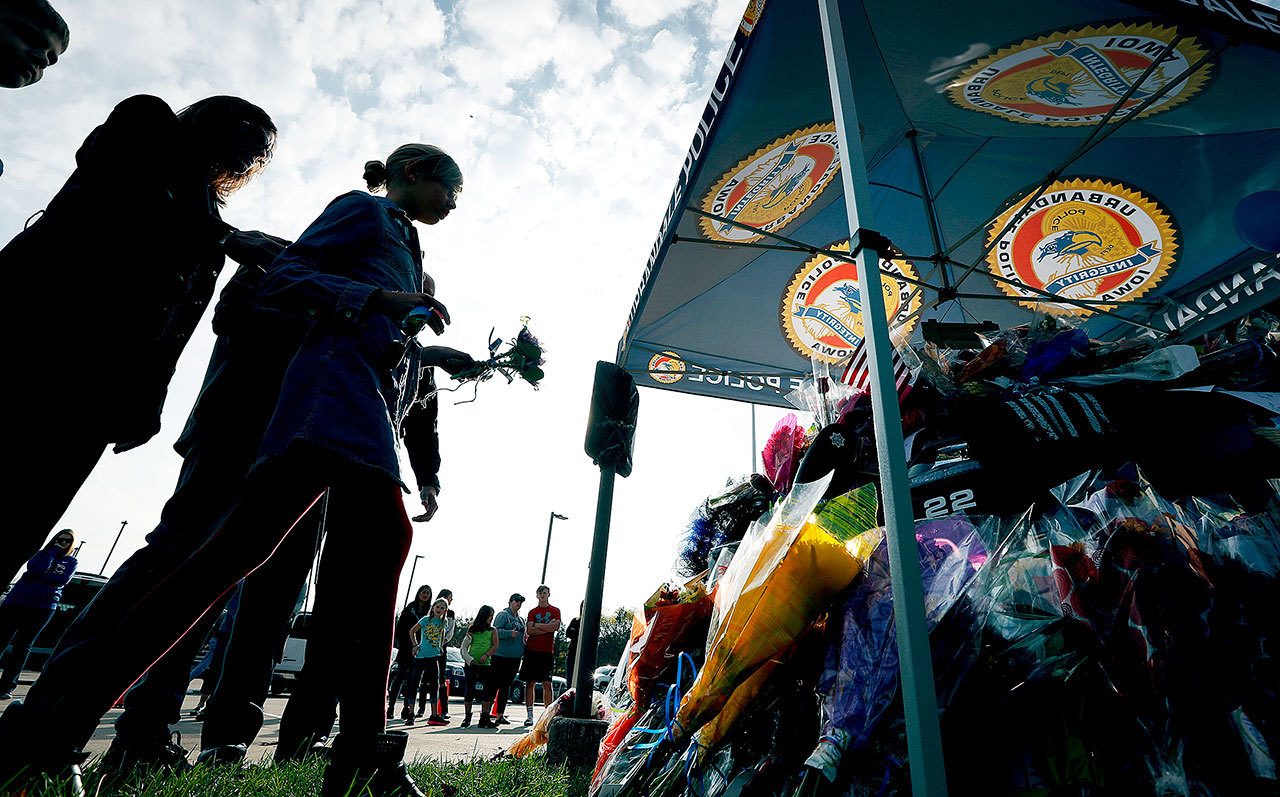 Local residents place flowers on a memorial outside the Urbandale Police Department on Wednesday in Urbandale, Iowa. Urbandale officer Justin Martin and Des Moines officer Sgt. Anthony Beminio were ambushed and fatally shot in separate attacks Wednesday as they sat in their patrol cars, authorities said. (AP Photo / Charlie Neibergall)