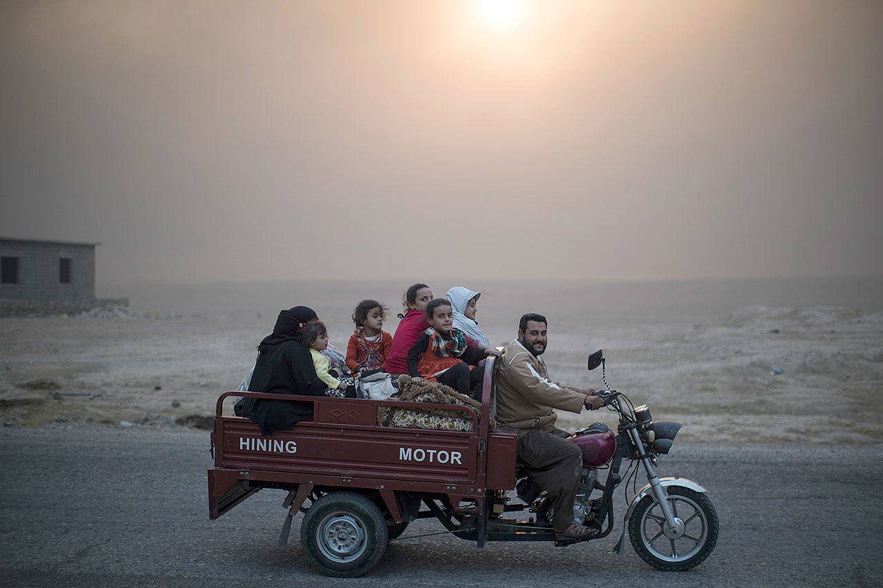 A displaced Iraqi family rides back to their home at the outskirts of Qayara, south of Mosul, Iraq, on Thursday. A senior military commander says more than 5,000 civilians have been evacuated from newly-retaken eastern parts of the Islamic State group-held city of Mosul and taken to camps. (Felipe Dana / Associated Press)