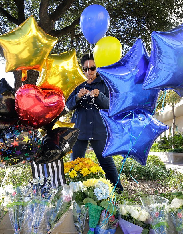 A woman leaves balloons at a make-shift memorial for slain San Antonio police officer Benjamin Marconi, 50, a 20-year veteran of the force, Monday, Nov. 21, in San Antonio. Marconi was fatally shot during a traffic stop near police headquarters Sunday. (AP Photo/Eric Gay)