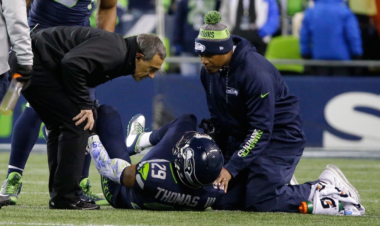Seahawks free safety Earl Thomas (29) is examined by team physician Dr. Ed Khalfayan (left) after injuring his leg in the first half of a game against the Panthers this past Sunday in Seattle. (AP Photo/Ted S. Warren)