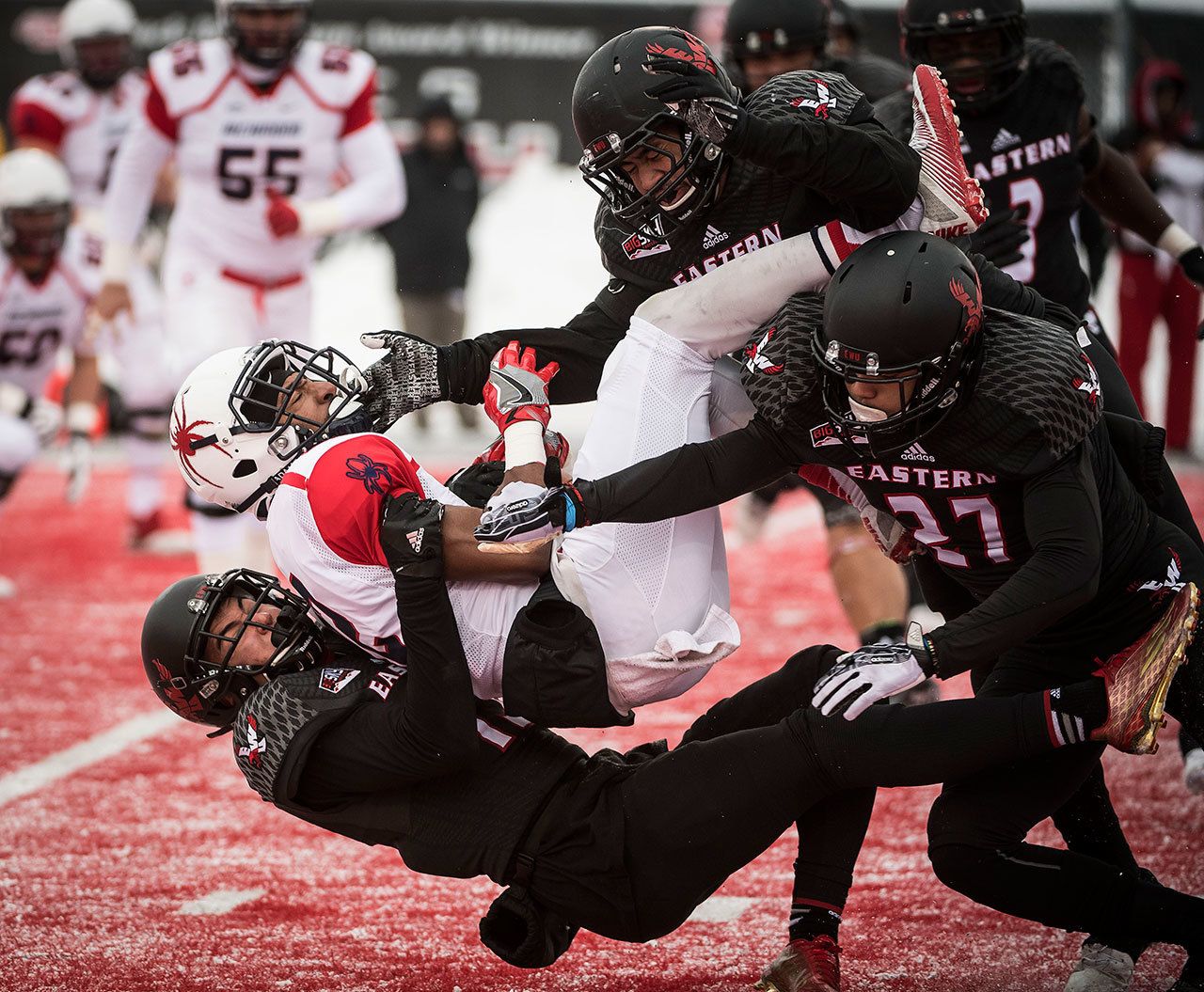Richmond wide receiver Brian Brown (12) is tackled by Eastern Washington defensive back Mitch Fettig (bottom), defensive back Victor Gamboa (27) and linebacker Miquiyah Zamora (top) during a FCS playoff game Saturday in Cheney. (Colin Mulvany/The Spokesman-Review via AP)