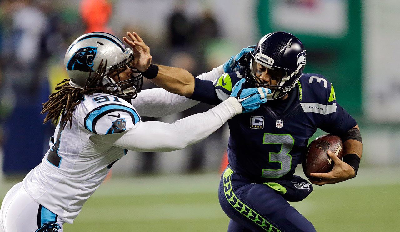 Seahawks quarterback Russell Wilson (3) stiff-arms the Panthers’ Ryan Delaire as he runs with the ball in the first half of a game Dec. 4 in Seattle. (AP Photo/Stephen Brashear)