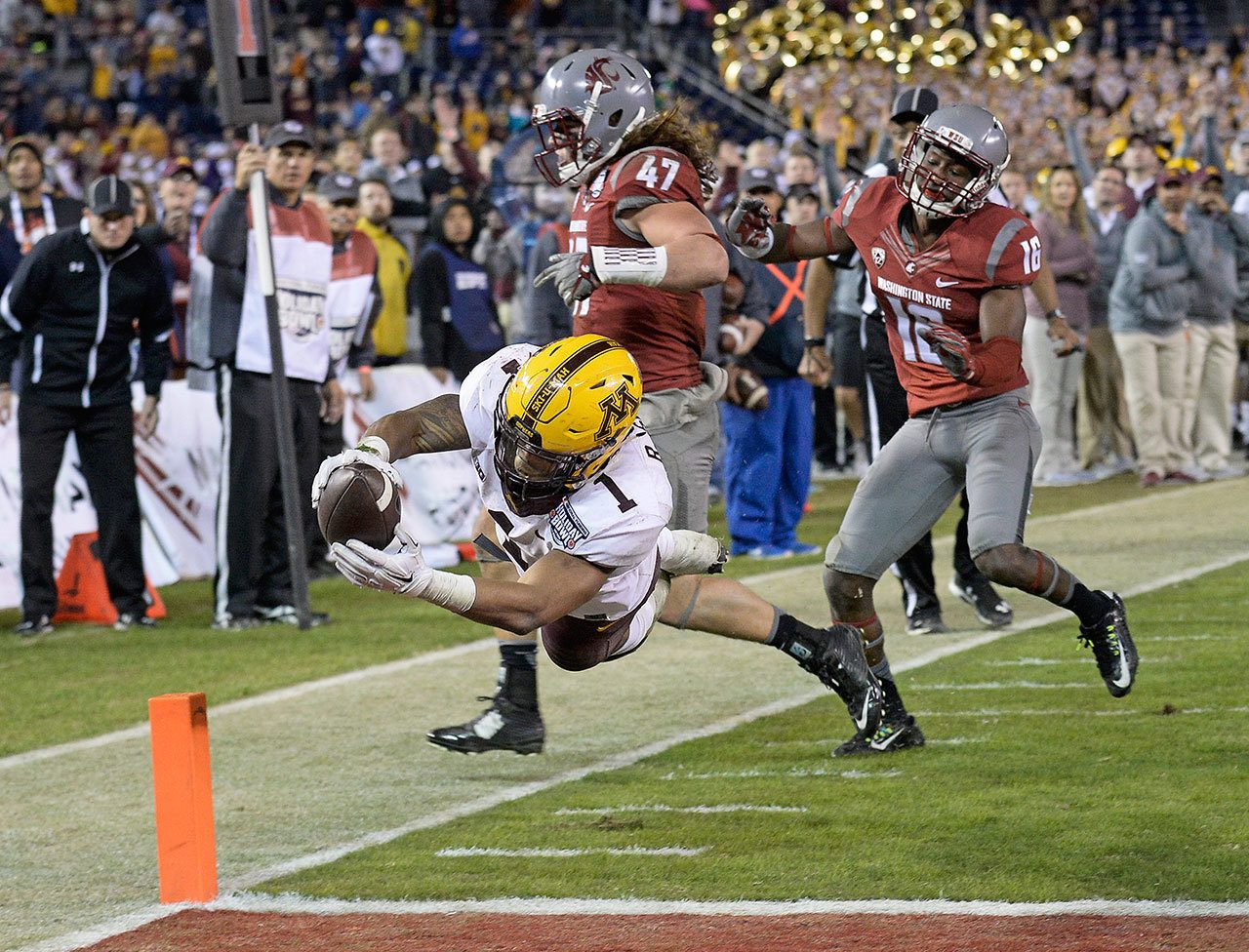 Minnesota running back Rodney Smith dives into the end zone for a touchdown past the defense of Washington State linebacker Peyton Pelluer (47) and cornerback Treshon Broughton (16) during the second half of Tuesday’s Holiday Bowl in San Diego. (AP Photo/Denis Poroy)