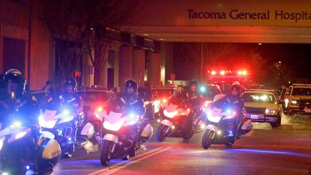 Motorcycle law enforcement officers lead a procession away from Tacoma General Hospital of an ambulance bearing the body of	Tacoma police officer Reginald “Jake” Gutierrez, who was shot and killed while answering a domestic violence call Wednesday in Tacoma. Tacoma police spokeswoman Loretta Cool said Gutierrez was pronounced dead at the hospital Wednesday evening. “We’ve suffered a great loss and I think the community has suffered a great loss. I don’t know how to put that into words,” Cool said. (AP Photo/Ted S. Warren)
