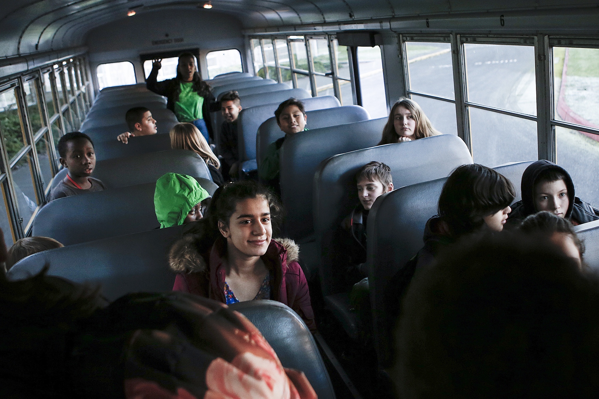 Evergreen Middle School student Tabarek Al-Jubouri (center left) sits on a school bus with her fellow classmates before departing the following after-school activities Dec. 6. An annual fundraiser allows all students at Evergreen to participate in extracurricular activities by providing extra buses. (Ian Terry / The Herald)