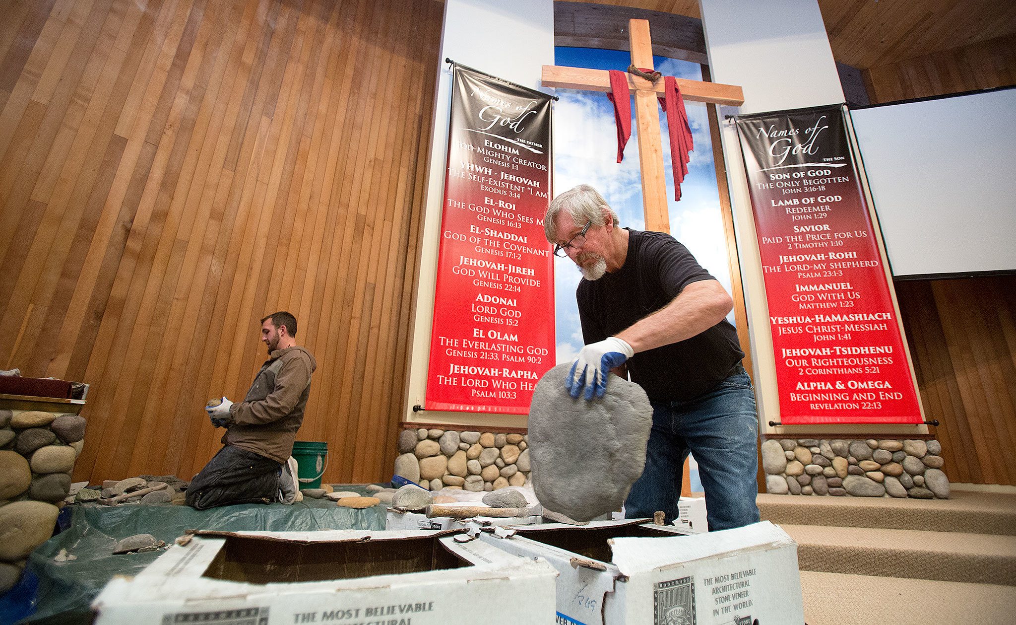 Mason Chuck Hein, of Chuck’s Masonry, picks through boxes of river rock to find the right piece for lining the baptistry at Calvary Baptist Church on Colby in Everett on Wednesday as his son, Harley, works along with him. (Andy Bronson / The Herald)