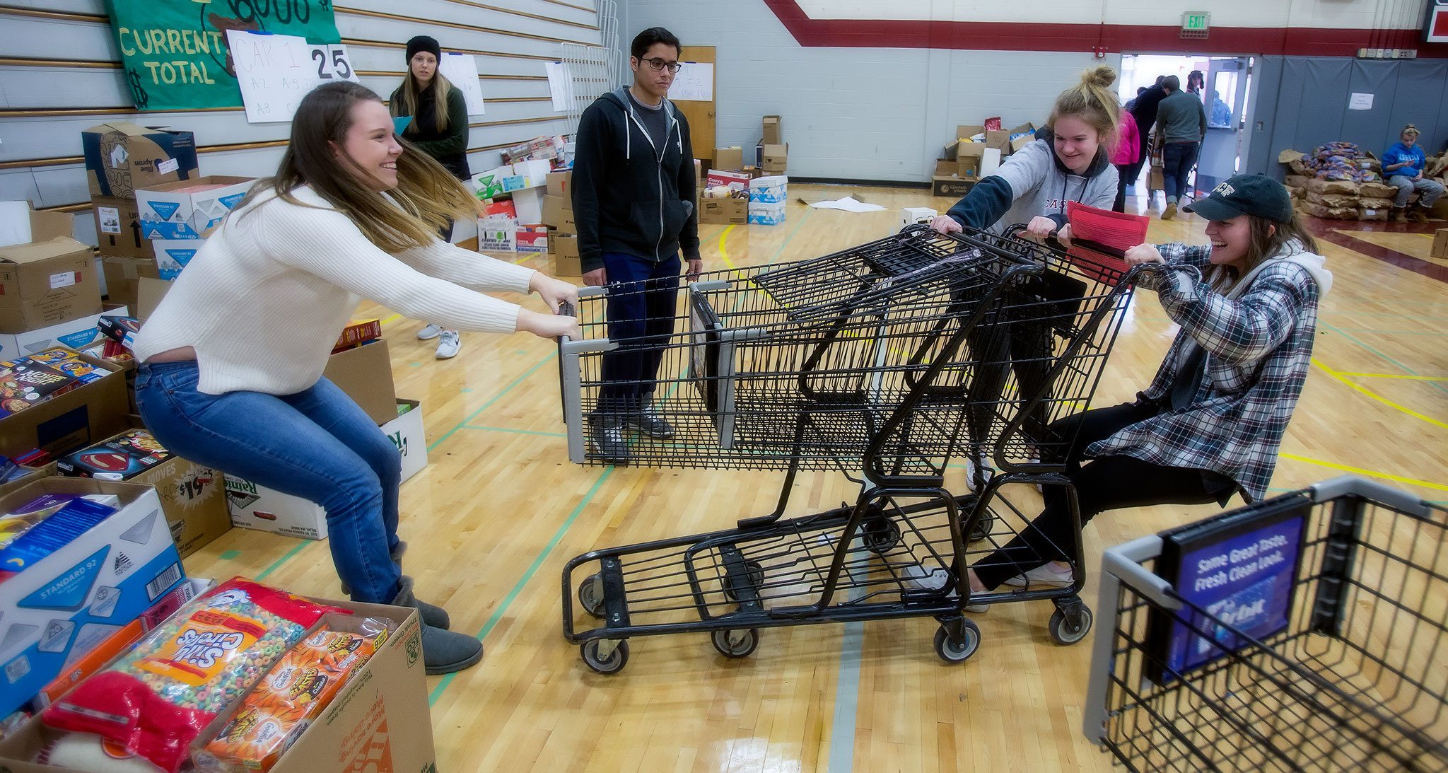 Ricki Davis, left, and Katie Helmke and Alex Cizek, right, try to pull apart two stuck shopping carts as students, alumni and volunteers gather and deliver food from Cascade High School on Wednesday, Dec. 14, 2016 in Everett, Wa. (Andy Bronson / The Herald)