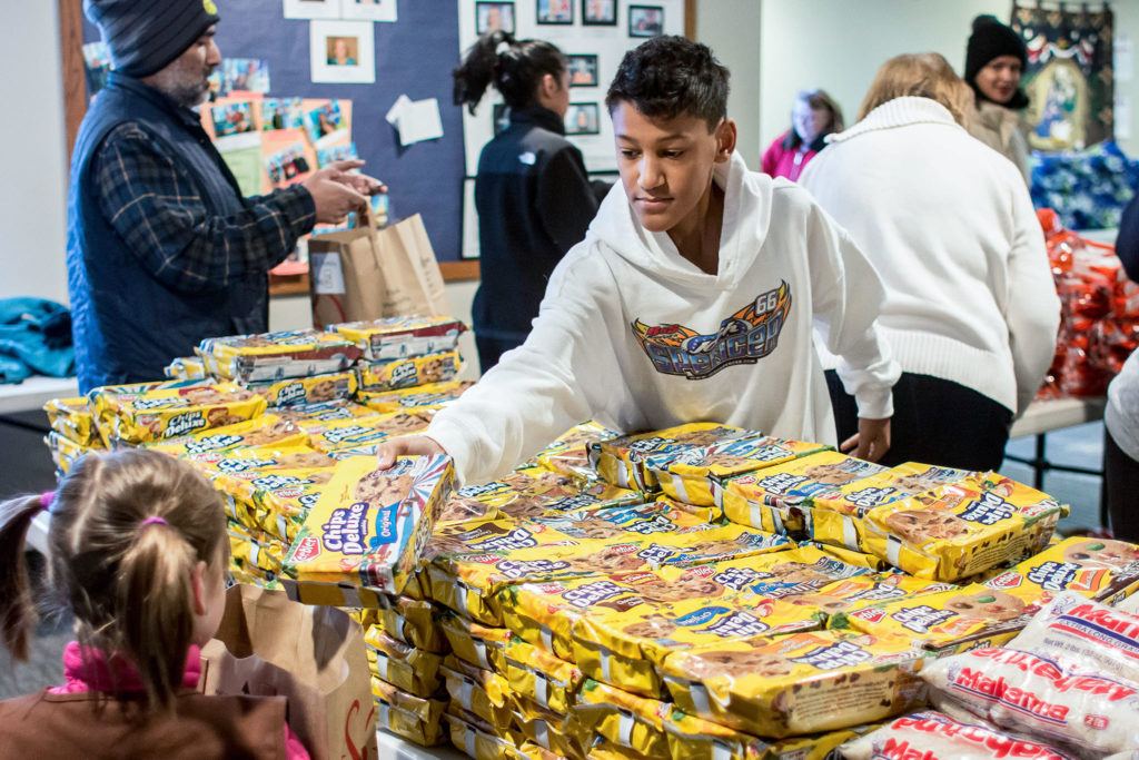 Gavin Clements distributes snacks as part of the Advent Lutheran Church holiday Food Baskets Program in Mill Creek on Dec. 16, 2016. Volunteers provided holiday meals with frozen turkeys to 225 families in south Snohomish County. (Bill Trueit / For the Herald)
