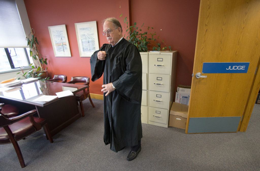 Snohomish County Superior Court Judge Thomas Wynne zips up his robe before court proceedings Dec. 12 in Everett over a parent wanting to move a child out of state. Judge Wynne is retiring next month. (Andy Bronson / The Herald)
