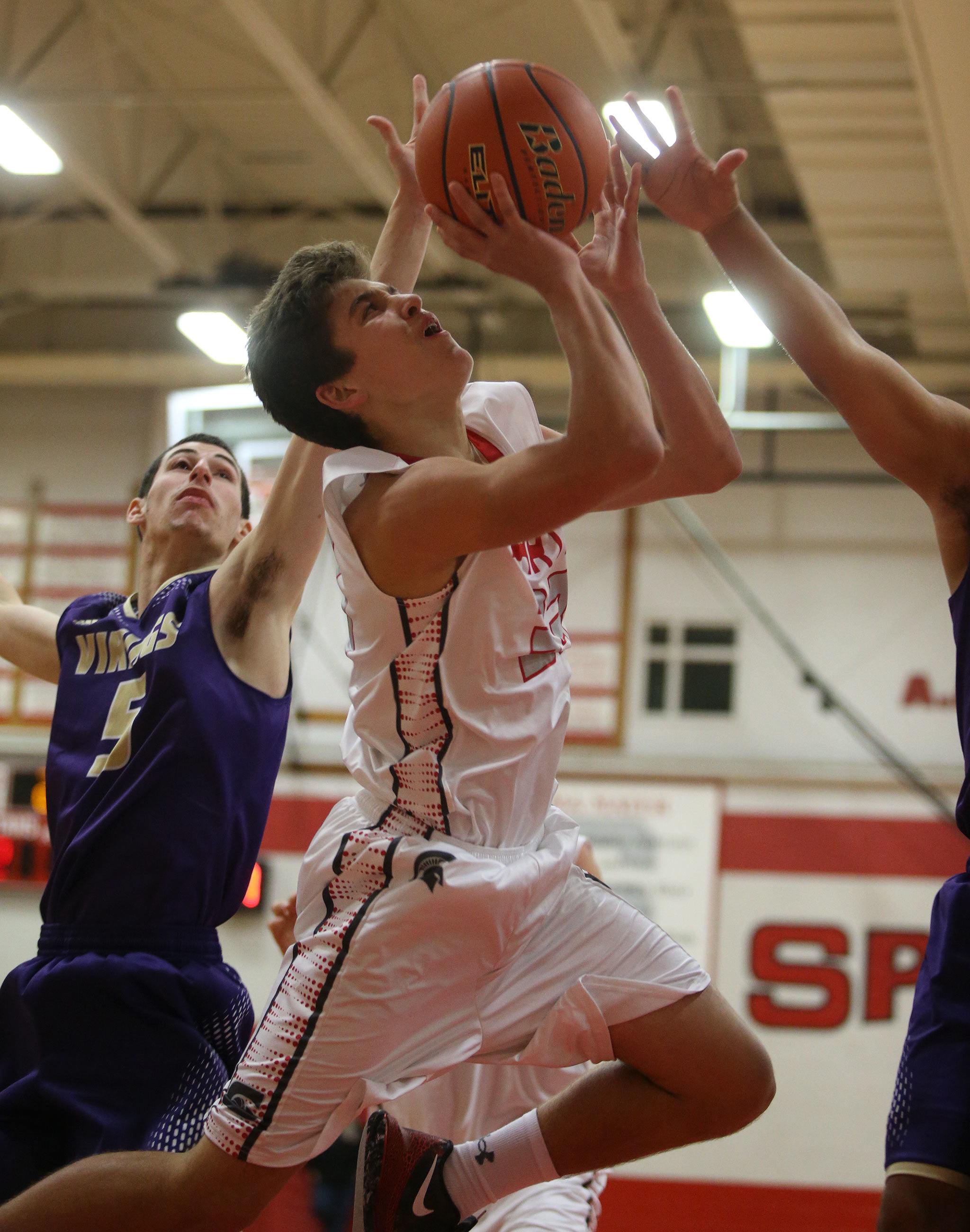 Stanwood’s Nate Kummer is fouled as he goes up for a shot during a game against Lake Stevens on Tuesday in Stanwood. The Spartans won 74-51. (Andy Bronson / The Herald)
