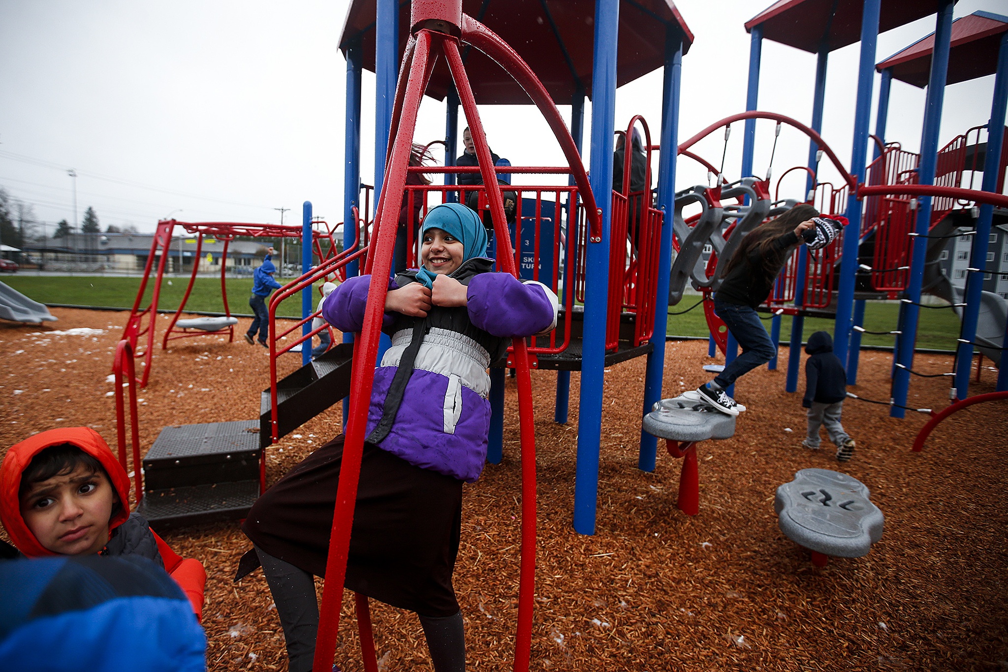 Rihab Alghazali (center), 10, swings around on Hawthorne Elementary School’s new playground that opened Saturday afternoon in Everett. (Ian Terry / The Herald)