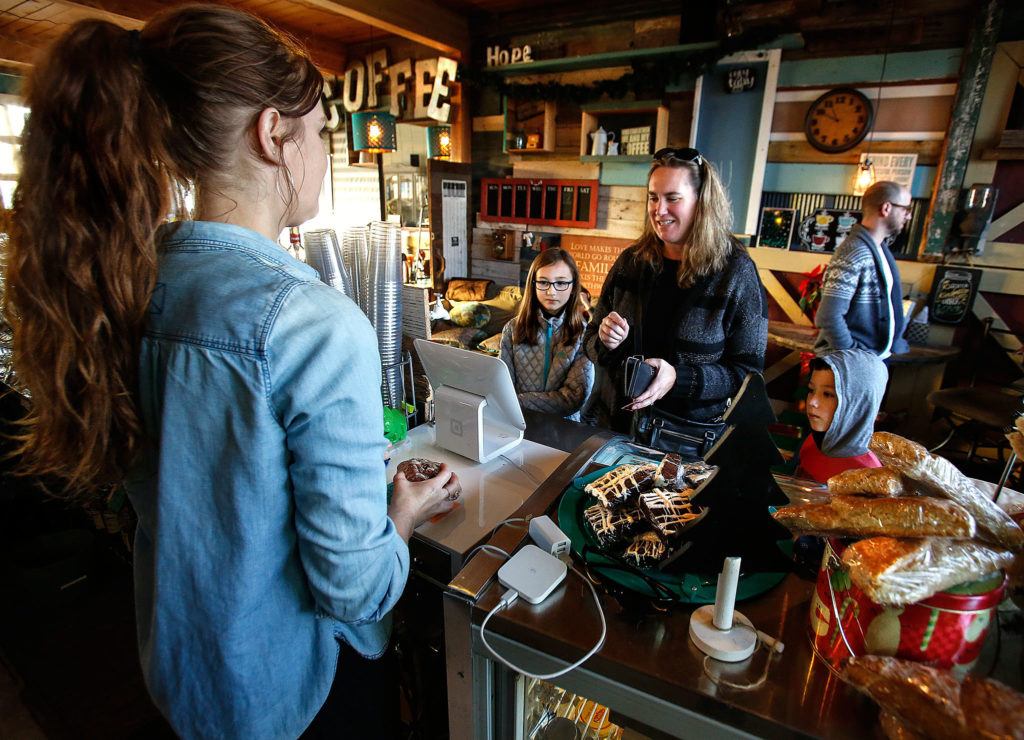 Volunteer Colleen Goad (left) serves customer Liha Rinehardt and her daughter, Maggie, 9 (left facing) and son, Spencer, 6, Wednesday morning in The Living Room Coffee House. The Rinehardt family recently moved to Marysville from Everett. (Dan Bates / The Herald)
