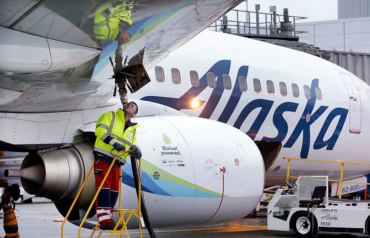 In this Nov. 14 photo, fueling manager Jarid Svraka looks on as he fuels an Alaska Airlines Boeing 737-800 jet with a new, blended alternative jet fuel, at Seattle-Tacoma International Airport in SeaTac. On Tuesday, Dec. 6, Alaska Airlines said it has won government approval to buy rival Virgin America after agreeing to reduce its flight-selling partnership with American Airlines. (AP Photo/Elaine Thompson, File)