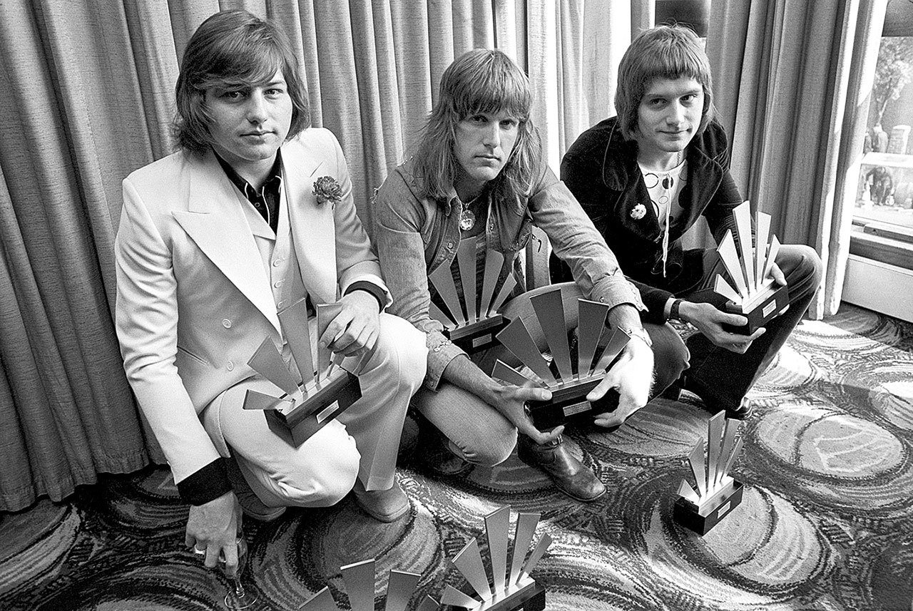 This Sept. 30, 1972 photo of the members of the rock band Emerson, Lake and Palmer shows Greg Lake (left), Keith Emerson (center) and Carl Palmer after an award ceremony in London. Greg Lake, the prog-rock pioneer who co-founded King Crimson and Emerson, Lake and Palmer, died Wednesday, Dec. 7, after “a long and stubborn battle with cancer,” according to his manager. (PA File via AP)