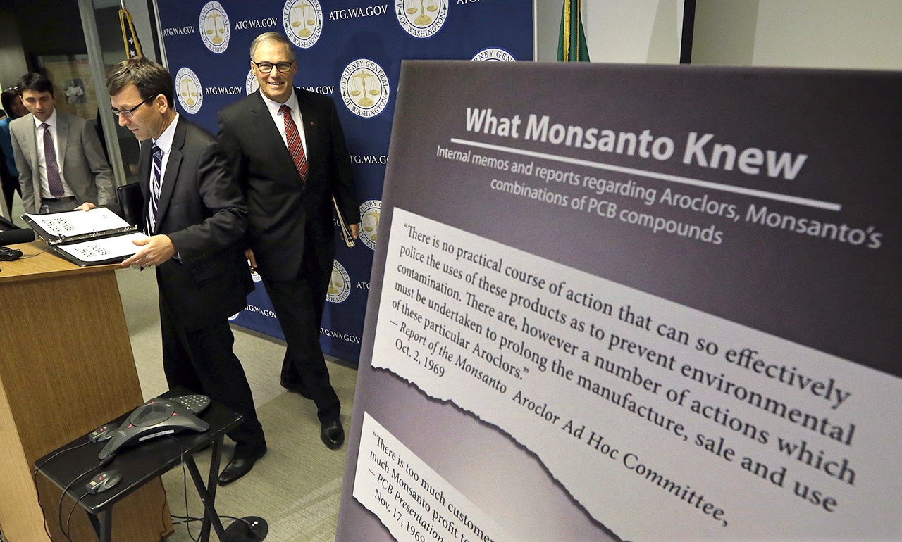 Washington Attorney General Bob Ferguson (left) and Gov. Jay Inslee head into a news conference where Ferguson announced a lawsuit against agrochemical giant Monsanto over pollution from PCBs, on Thursday, Dec. 8, in Seattle. (AP Photo/Elaine Thompson)