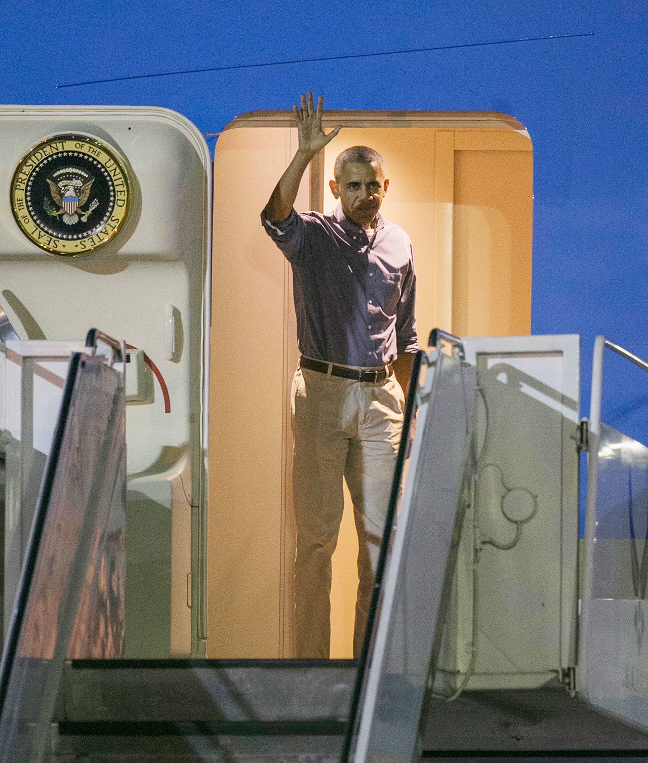 U.S. President Barack Obama waves as he exits Air Force One at Joint Base Pearl Harbor-Hickam, on Friday, Dec. 16, in Honolulu. (AP Photo/Marco Garcia)