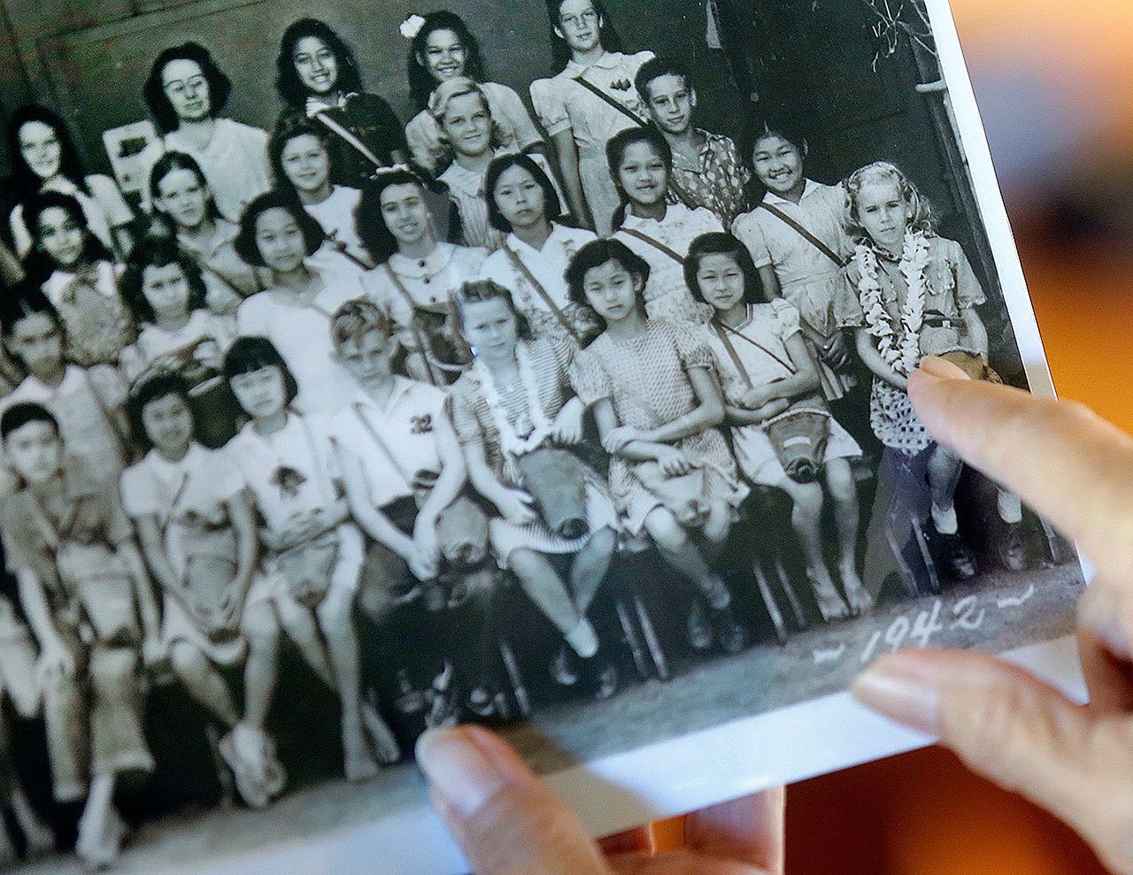 Joan Rodby points to herself in a 1942 photo, in Makawao, Hawaii, on Nov. 18. After the Pearl Harbor attack, schools required students to carry gas masks with them at all times — even when posing for their class photo. (AP Photo/Rick Bowmer)