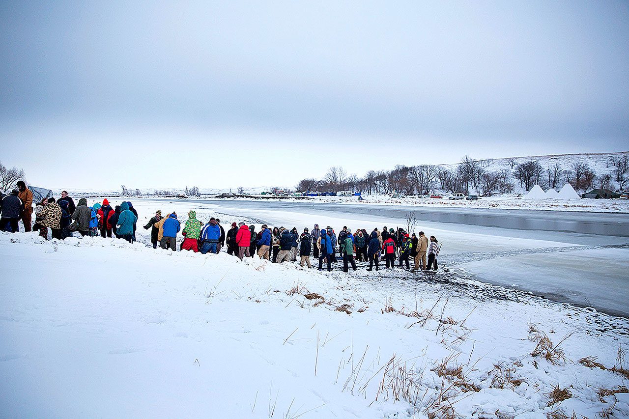 A procession makes its way down to the Cannonball River to take part in a Native American water ceremony at the Oceti Sakowin camp where people have gathered to protest the Dakota Access oil pipeline in Cannon Ball, North Dakota, on Friday, Dec. 2. (AP Photo/David Goldman)