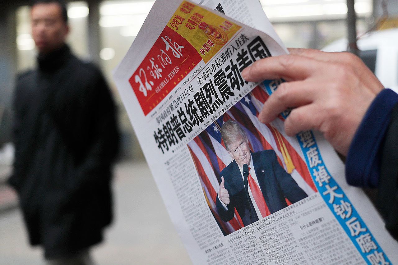 A man at a news stand in Beijing reads a newspaper on Nov. 10 with the headline of “U.S. President-elect Donald Trump delivers a mighty shock to America.” (AP Photo/Andy Wong)