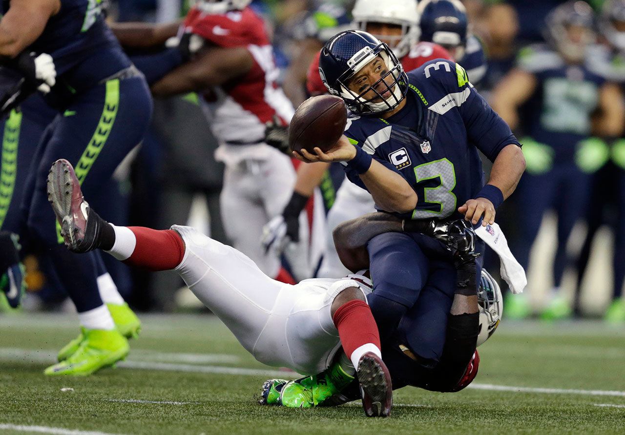 Seahawks quarterback Russell Wilson (3) is tackled by the Cardinals’ Sio Moore as he releases the ball in the second half of a game Saturday in Seattle. (AP Photo/John Froschauer)