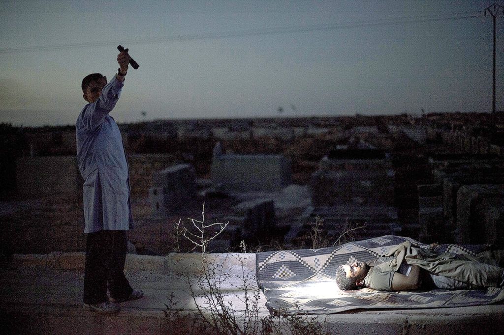 A man points a flashlight towards the body of a Syrian man killed by Syrian army shelling at a graveyard in Aleppo, Syria, on Oct. 13, 2012. (AP Photo/Manu Brabo, File)
