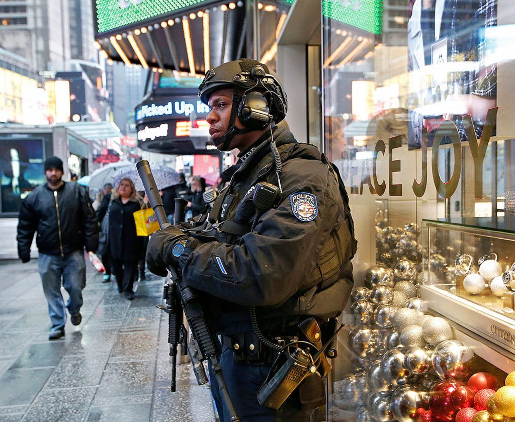 A heavily armed counterterrorism officer takes shelter beneath an overhang above a store in Times Square on Thursday, Dec. 2, in New York. (AP Photo/Kathy Willens)
