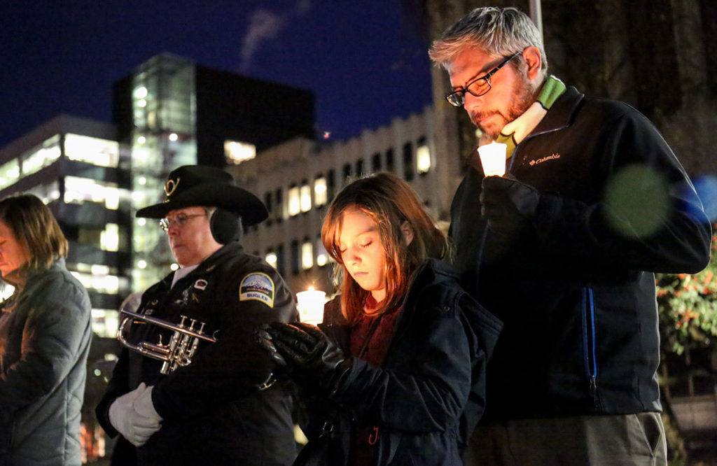 Bella Schulte, 9, and Michael Schulte bow their heads in prayer Wednesday night in Everett during Snohomish County’s Homeless Person’s Memorial Day, which featured a special tribute to veterans. (Kevin Clark / The Herald)
