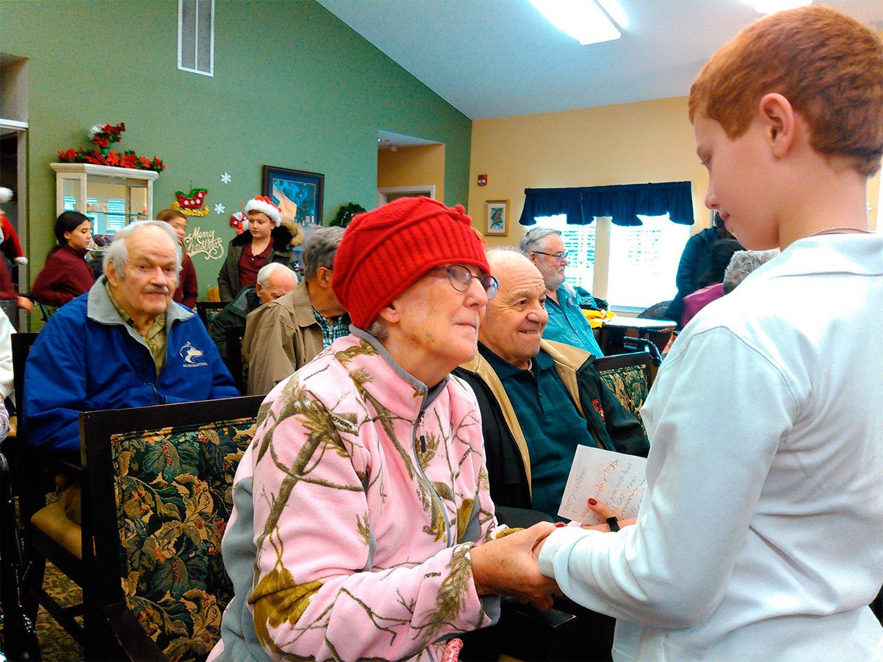 St. Michael Catholic School student Ian Benningfield presents a card to a resident of Pacifica Senior Living in Snohomish during a recent visit. (Contributed photo)