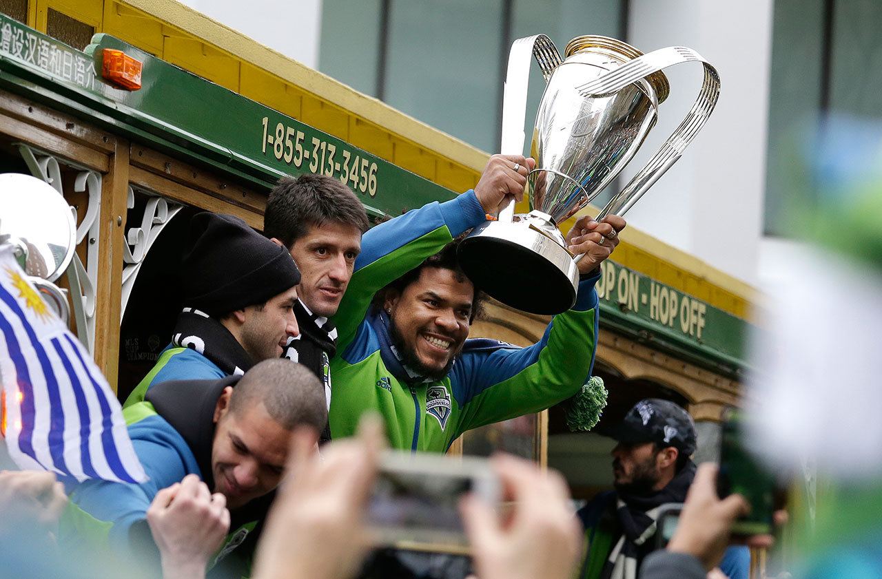 Sounders player Roman Torres holds the MLS Cup trophy as the team begins a parade through downtown Seattle on Tuesday. Seattle beat Toronto FC 5-4 in a penalty kick shootout Saturday to win its first MLS championship. (AP Photo/Elaine Thompson)