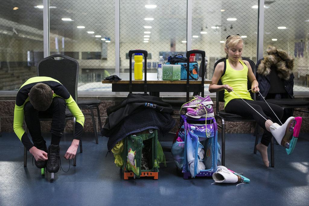 Kayla Black, 10, and her brother, Kamden, 13, lace up their skates prior to training at Olympic View Arena in Mountlake Terrace on Dec. 15. (Ian Terry / The Herald)

