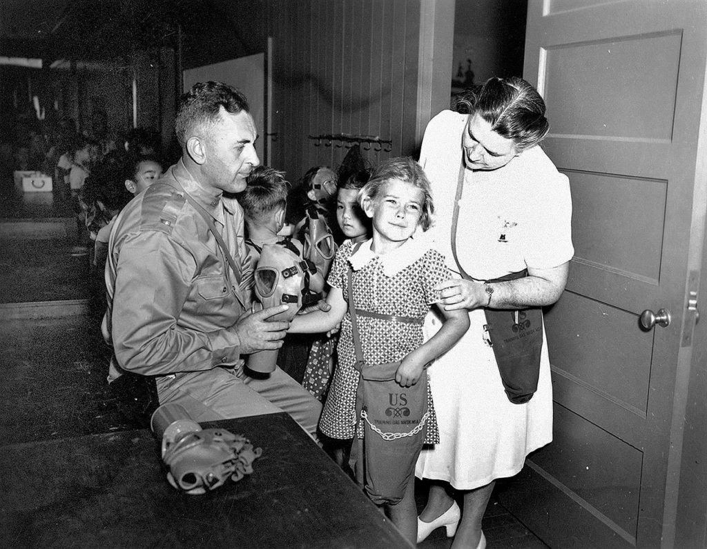 In this May 22, 1942 photo, students are fitted for gas masks at Kapalama School in Honolulu. Some saw their parents digging trenches outside their school. One Japanese student worried that her family would be taken to internment camps. (The Star-Advertiser via AP)
